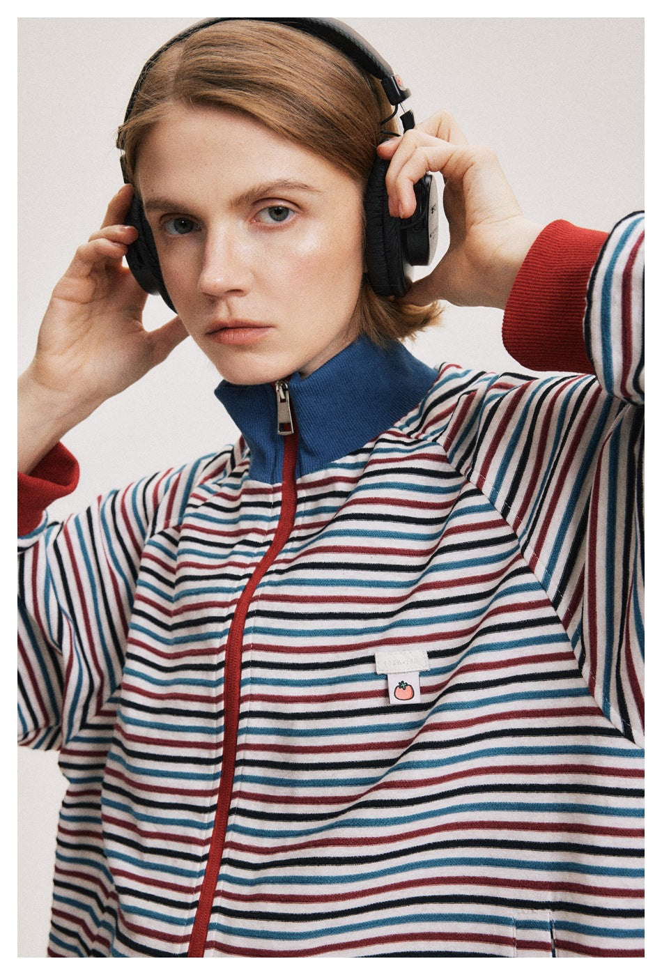 Close-up of the jacket's multicolor stripes, red zipper and cuffs, blue collar, and small tomato chest patch.