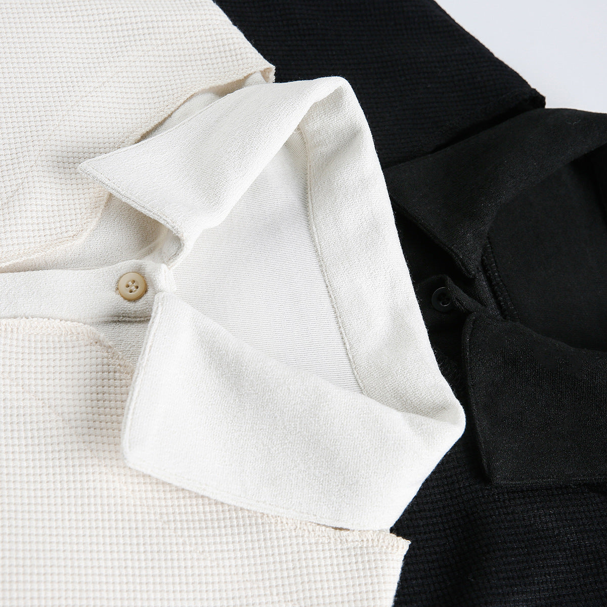 Close-up of white and black short-sleeve polo shirts, showing their collars and button plackets.