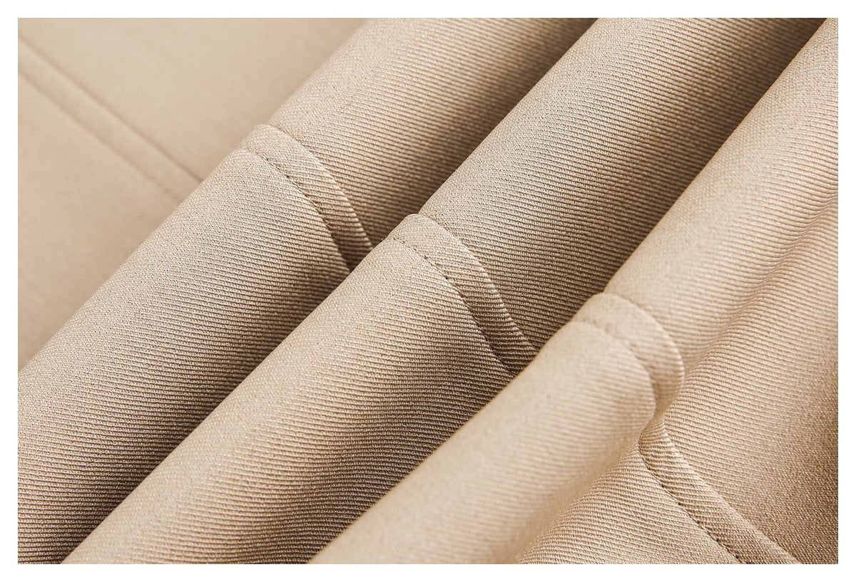 Close-up of folded beige garment fabric showing diagonal folds, fine texture, and stitched seams.