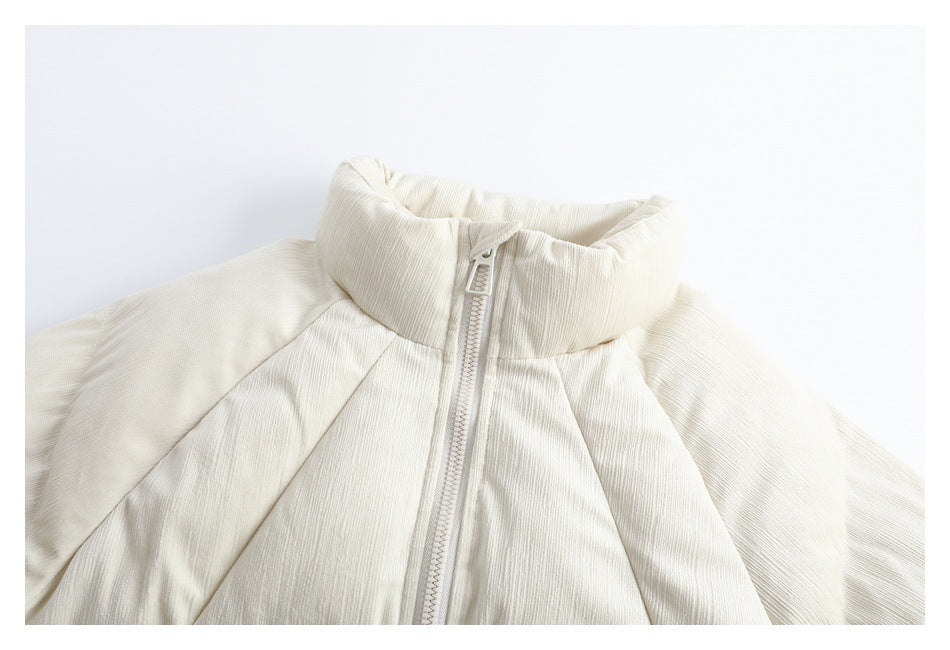 Close view of an ivory jacket front with a tall padded collar, center zipper, and raglan seams.