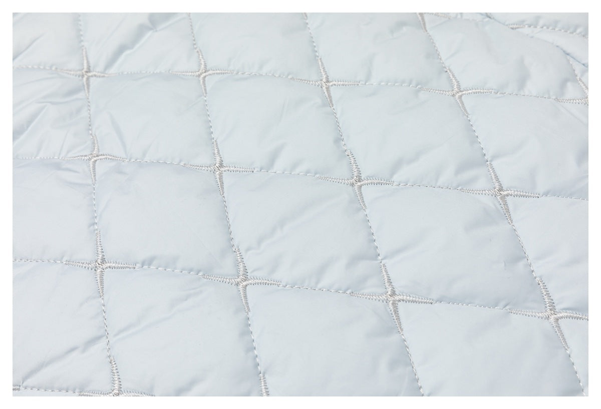 Close-up of pale blue quilted fabric with large stitched geometric panels.