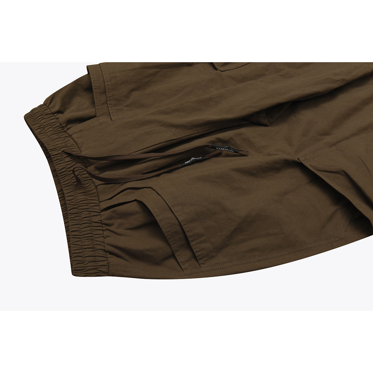 Close-up of olive-brown cargo pants showing the elastic waistband, drawstring and stitched pocket openings.