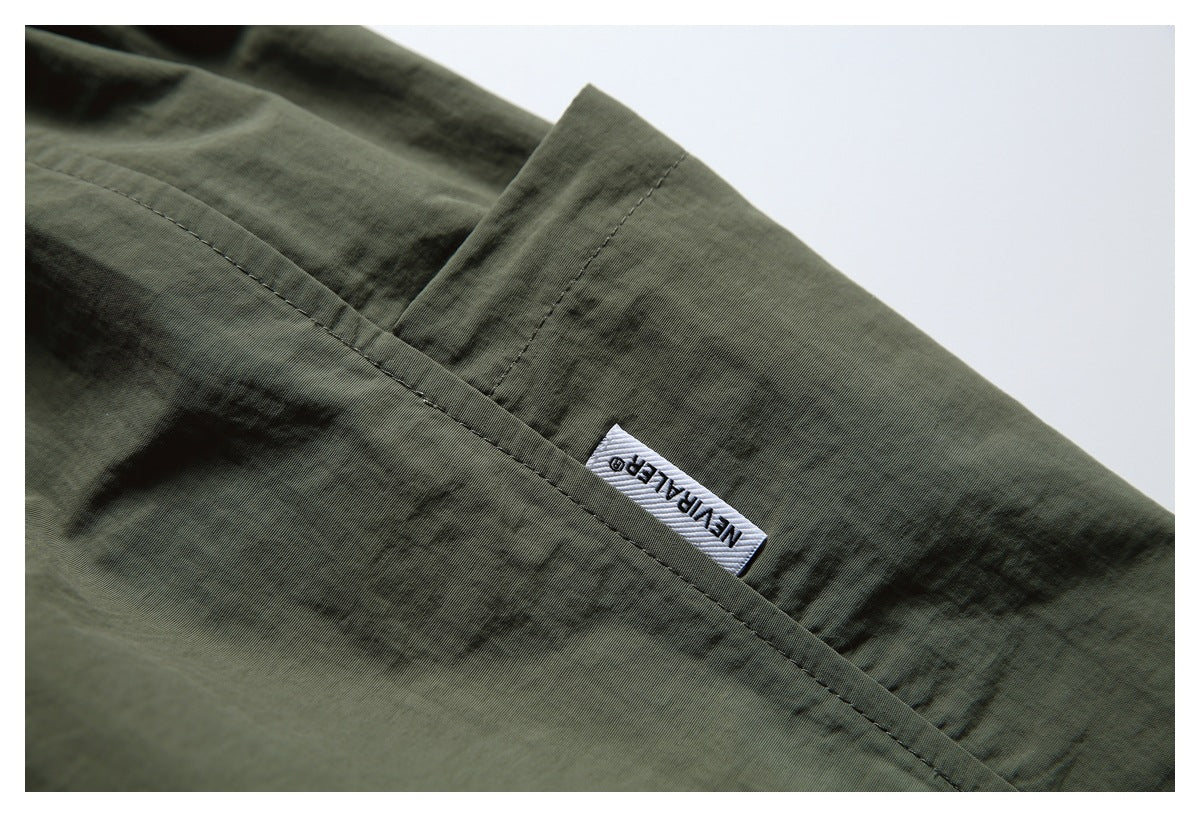 Close-up of a pocket seam and small woven label on dark olive shorts.