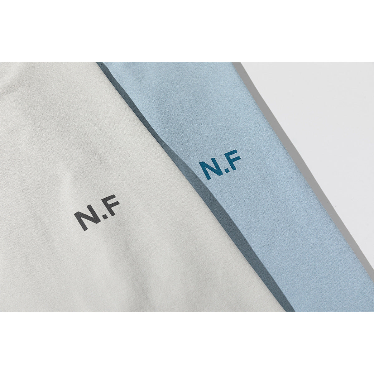 Close-up of light gray and blue T-shirts with small N.F chest prints.