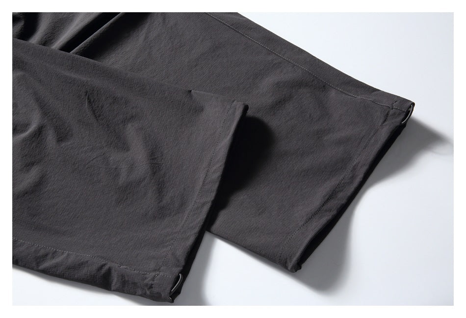 Close-up of the charcoal pants' stitched leg hem and folded fabric edge.