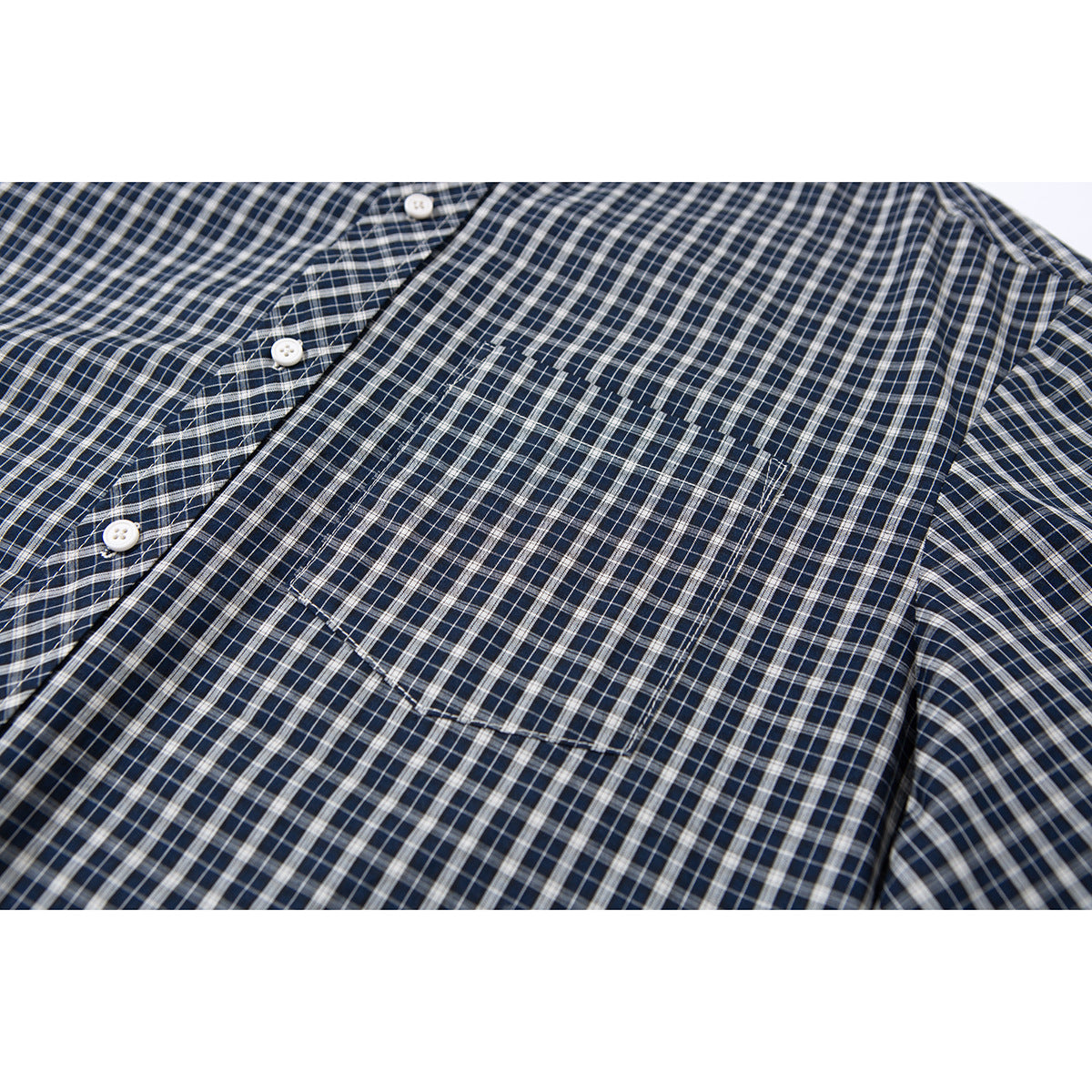 Close-up of a navy and gray plaid shirt's button placket and single chest pocket.