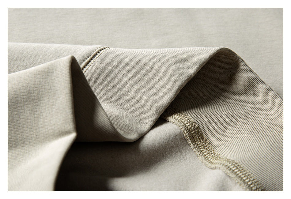 Inside close-up showing the light beige sweatshirt's ribbed edge and overlock stitching.