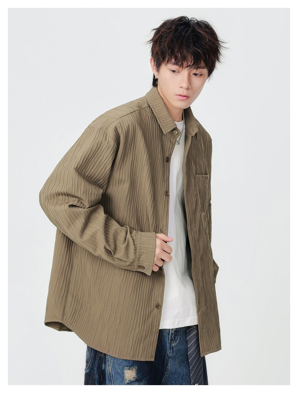Model wearing an oversized taupe ribbed button-up shirt with a chest pocket, shown from the front at an angle.