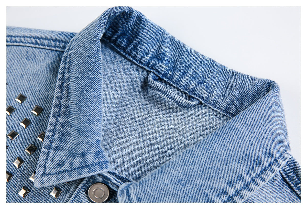 Close-up of a light blue denim jacket collar, metal snap, and square silver studs.