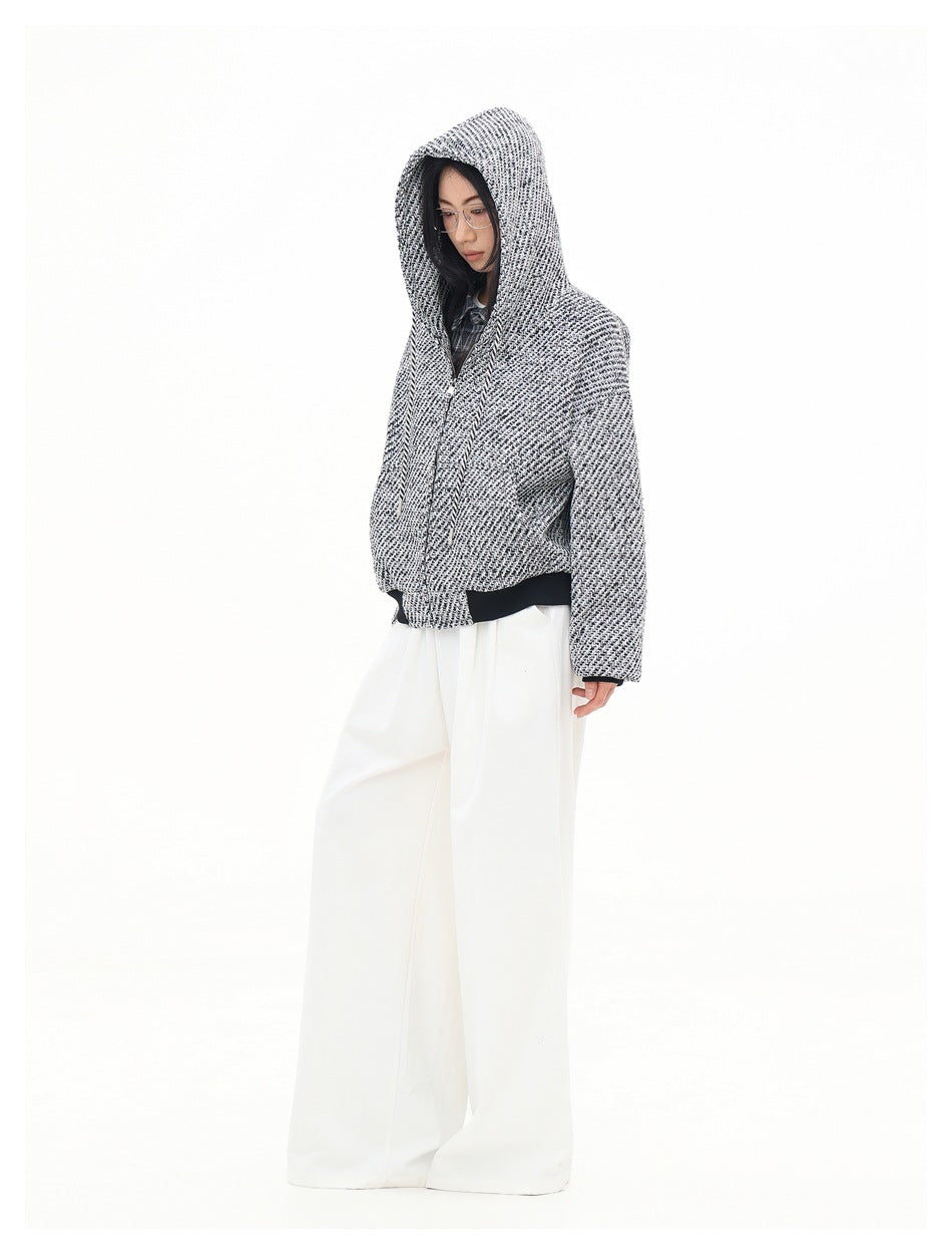 Three-quarter side view of a model wearing a black-and-white patterned hooded zip-up jacket.