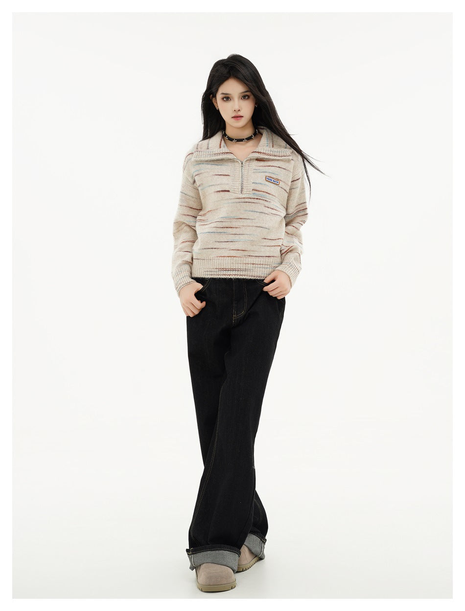 Full-length model wearing a beige knit pullover with thin multicolor stripes and wide-leg dark jeans.