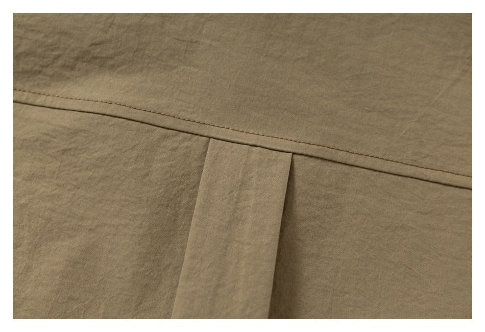 Close-up of a tan shirt's back yoke seam and center pleat.
