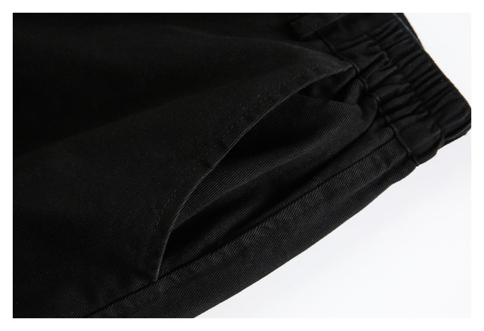 Close-up of black trousers showing a slanted pocket opening beside the gathered waistband.
