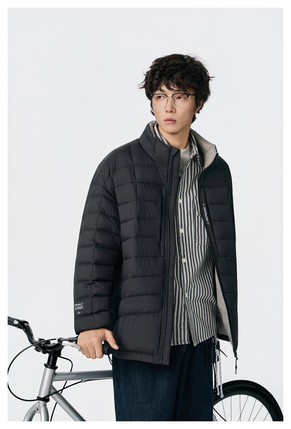 Close view of a model wearing an open black quilted jacket with a stand collar.