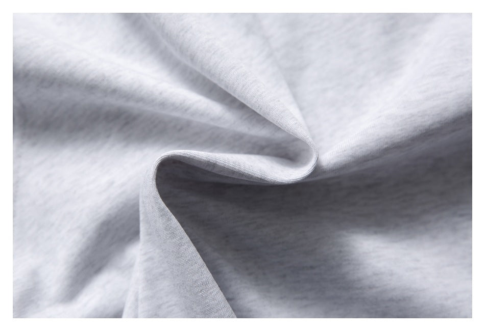 Close-up of light gray knit fabric draped into soft folds, showing its fine heathered texture.
