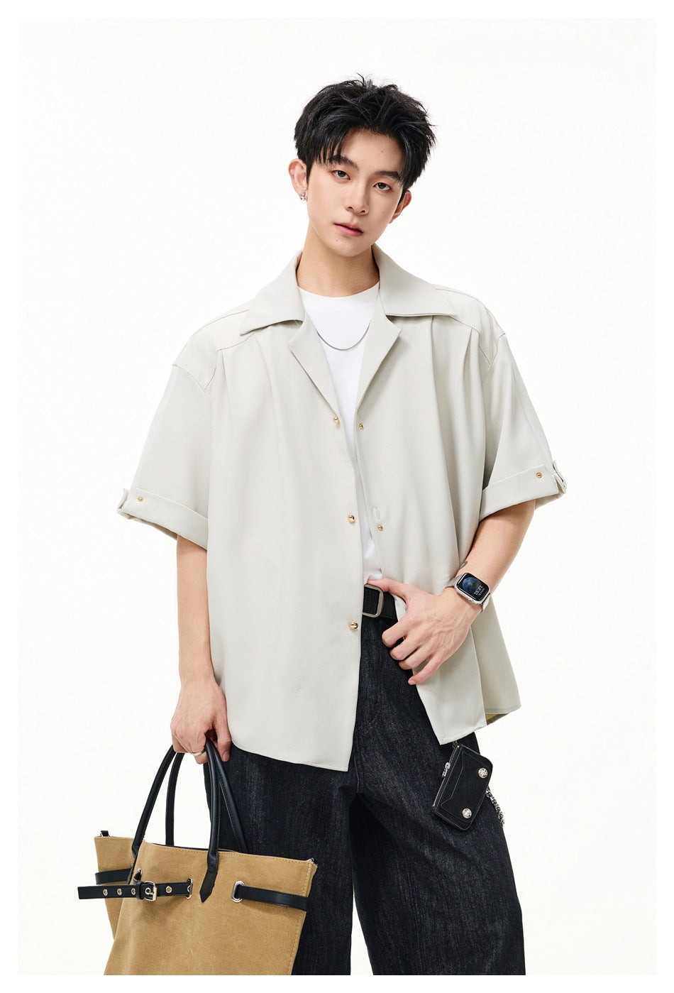 Model wearing a light cream oversized short-sleeve button-up shirt with wide lapels and rolled cuffs.