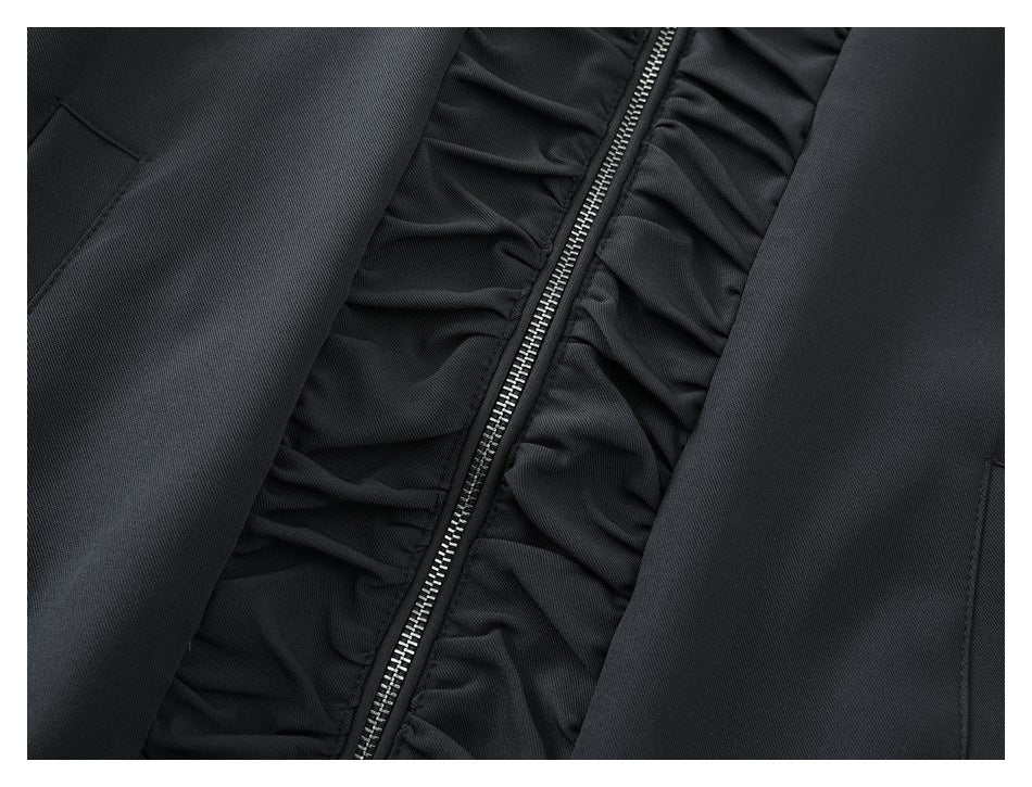 Close-up of the jacket's silver zipper and gathered trim between the front panels.