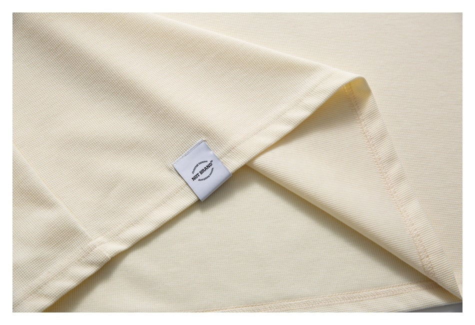 Close-up of the ivory polo's hem, interior stitching, and small sewn white label.