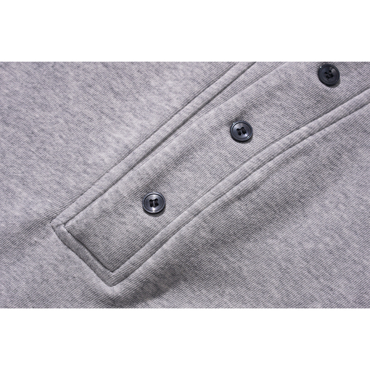 Close-up of a gray sweatshirt's three-button placket and knit texture.