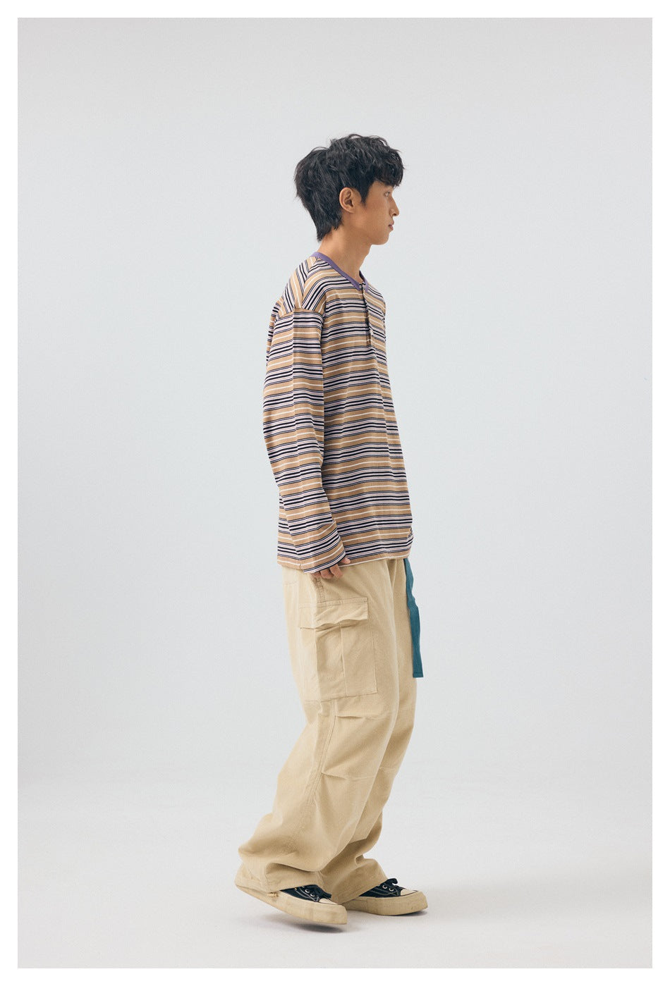 Model wearing the purple striped long-sleeve button-neck top with beige cargo pants, side view