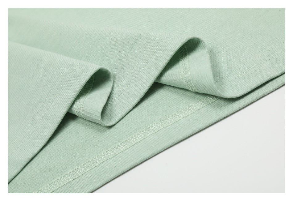 Close-up of pale mint-green fabric showing a folded edge and overlocked seam stitching.