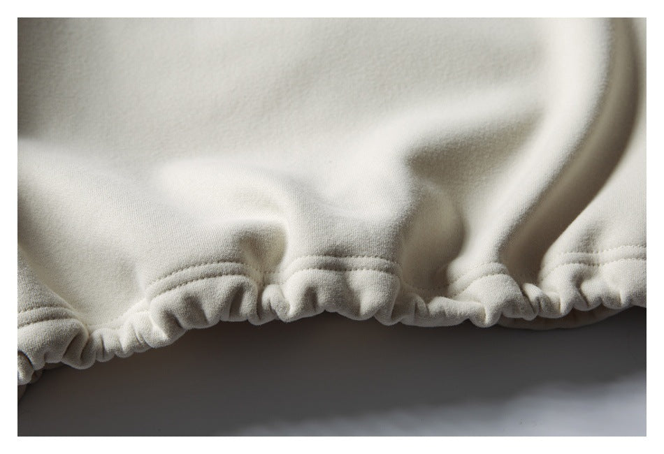 Close-up of the cream sweatshirt's gathered elastic hem and stitching.