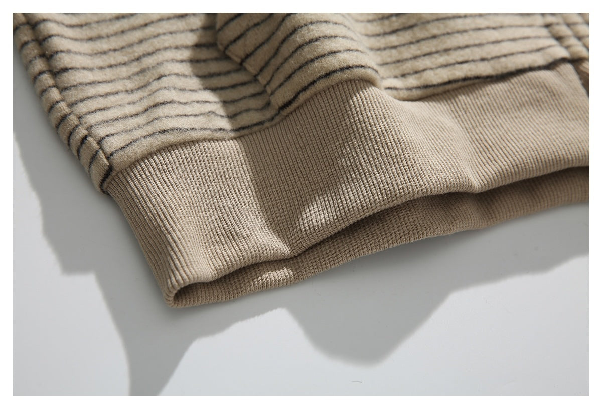 Close-up of the beige striped jacket's wide ribbed hem, shown folded on a white surface.