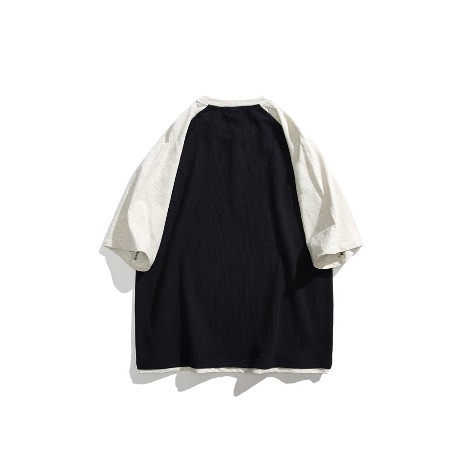Flat lay of the back of a black raglan shirt with light-colored sleeves.
