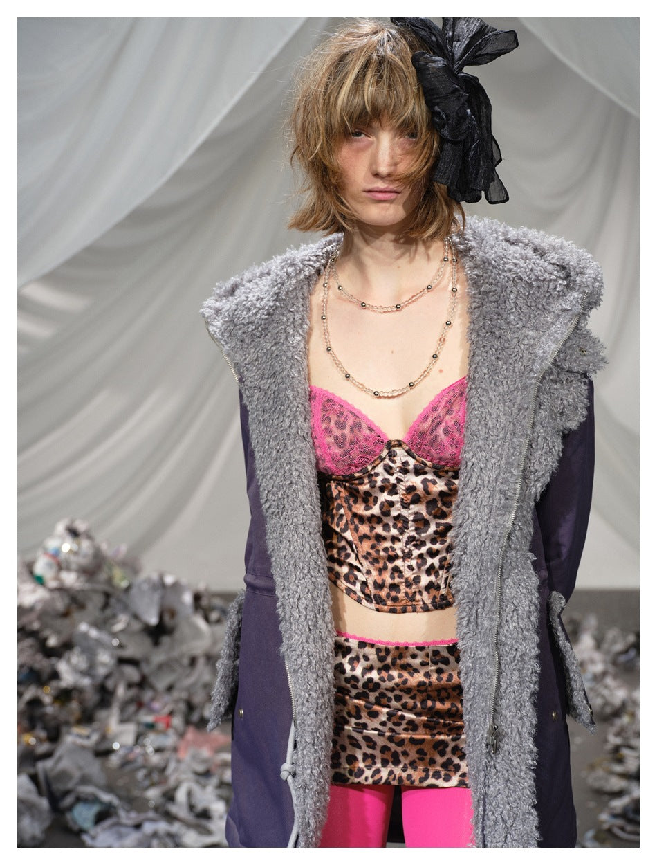 Model wearing a deep plum parka with thick gray textured trim over a pink and leopard-print outfit.