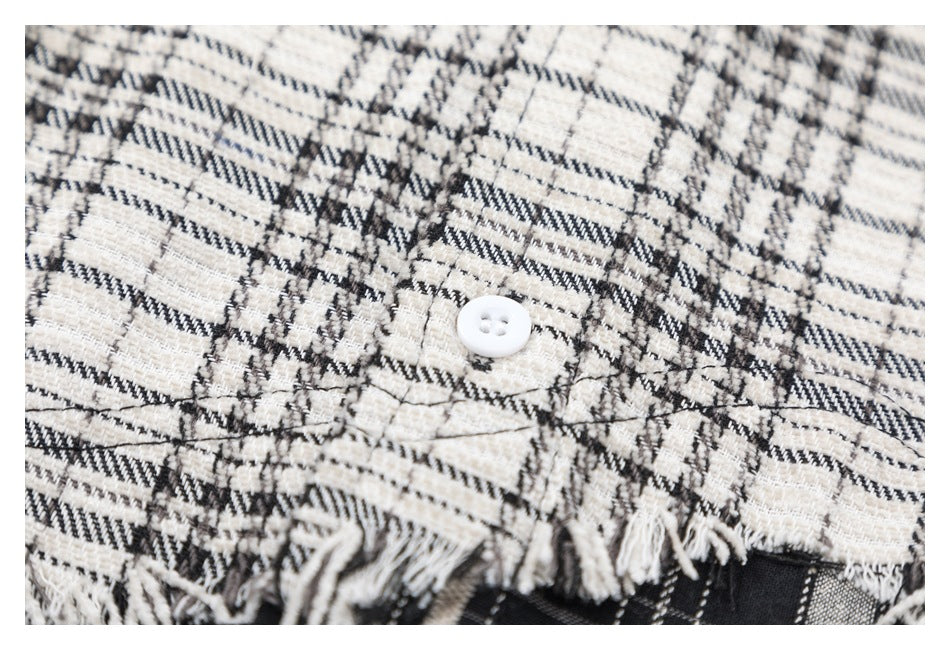 Close-up of a white button, plaid fabric, and frayed shirt hem.