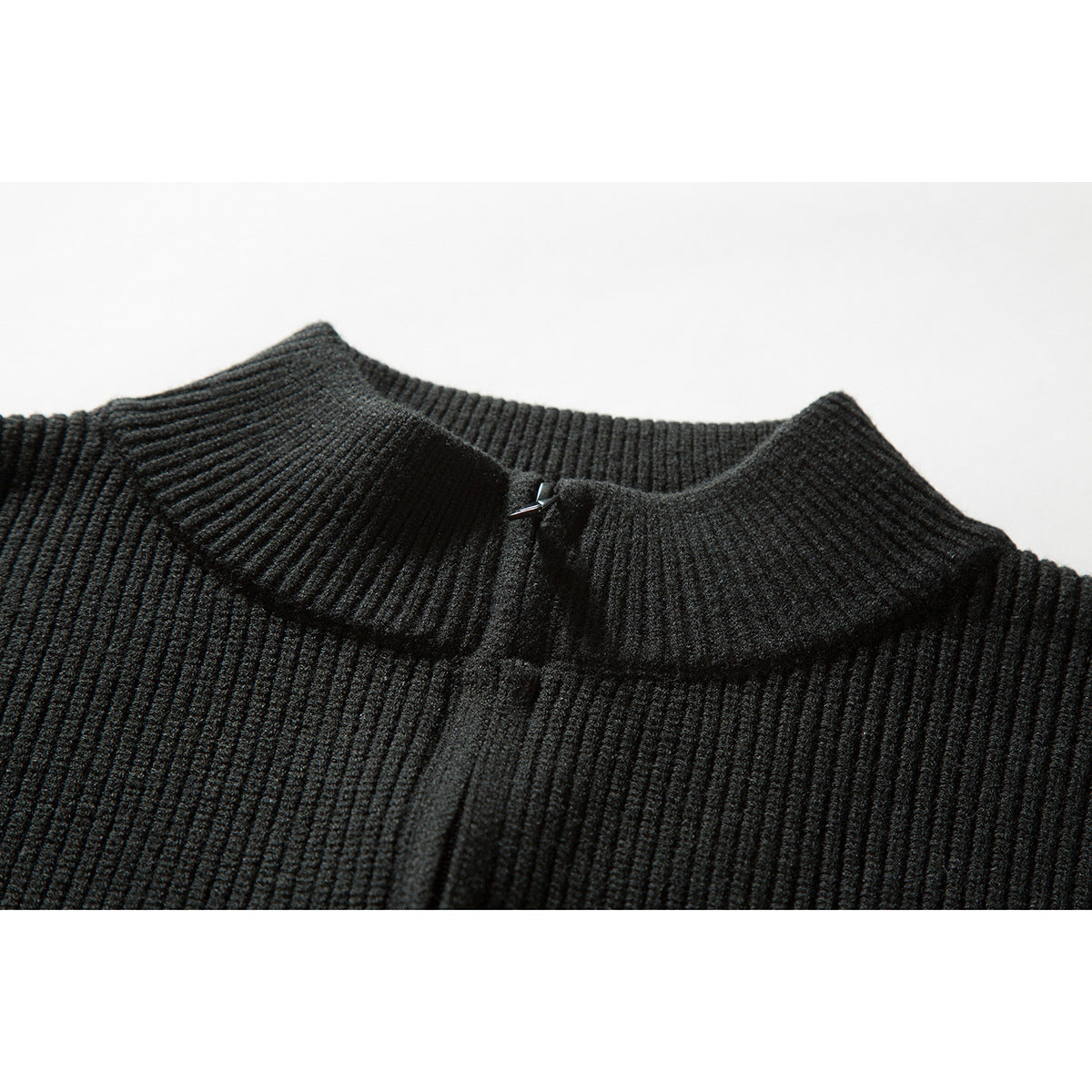 Close-up of a black rib-knit sweater collar with a small metal clasp.