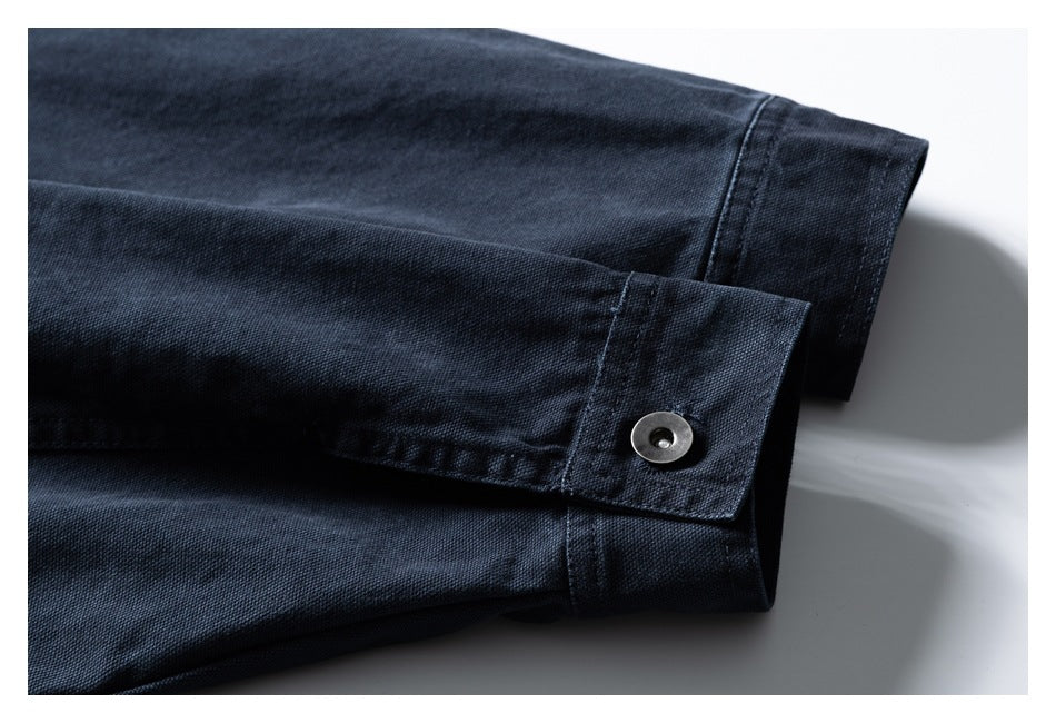 Close-up of a dark navy garment cuff with a metal snap button and stitched edges.