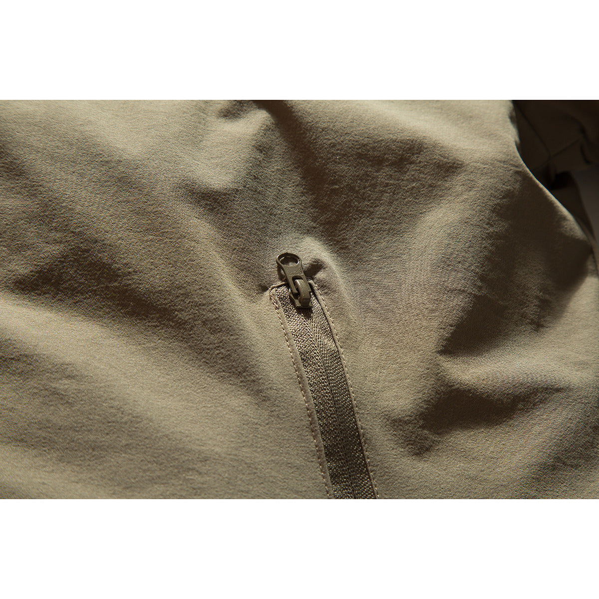Close-up of a tan jacket zipper and textured fabric.