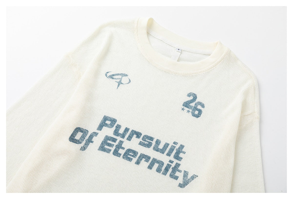 Cropped front view of an ivory knit crewneck shirt with blue “Pursuit of Eternity” lettering and a small 26 graphic.