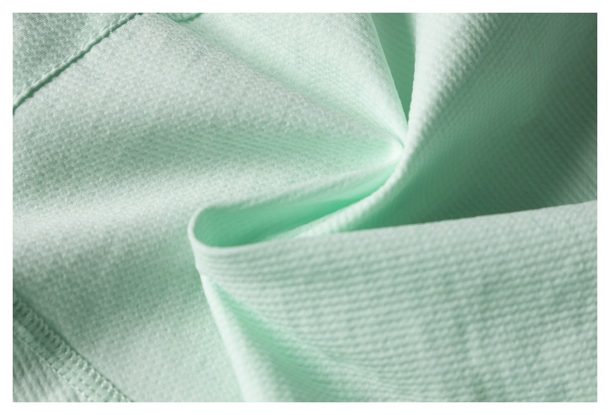 Close-up of pale mint textured garment fabric folded to show a finished edge.
