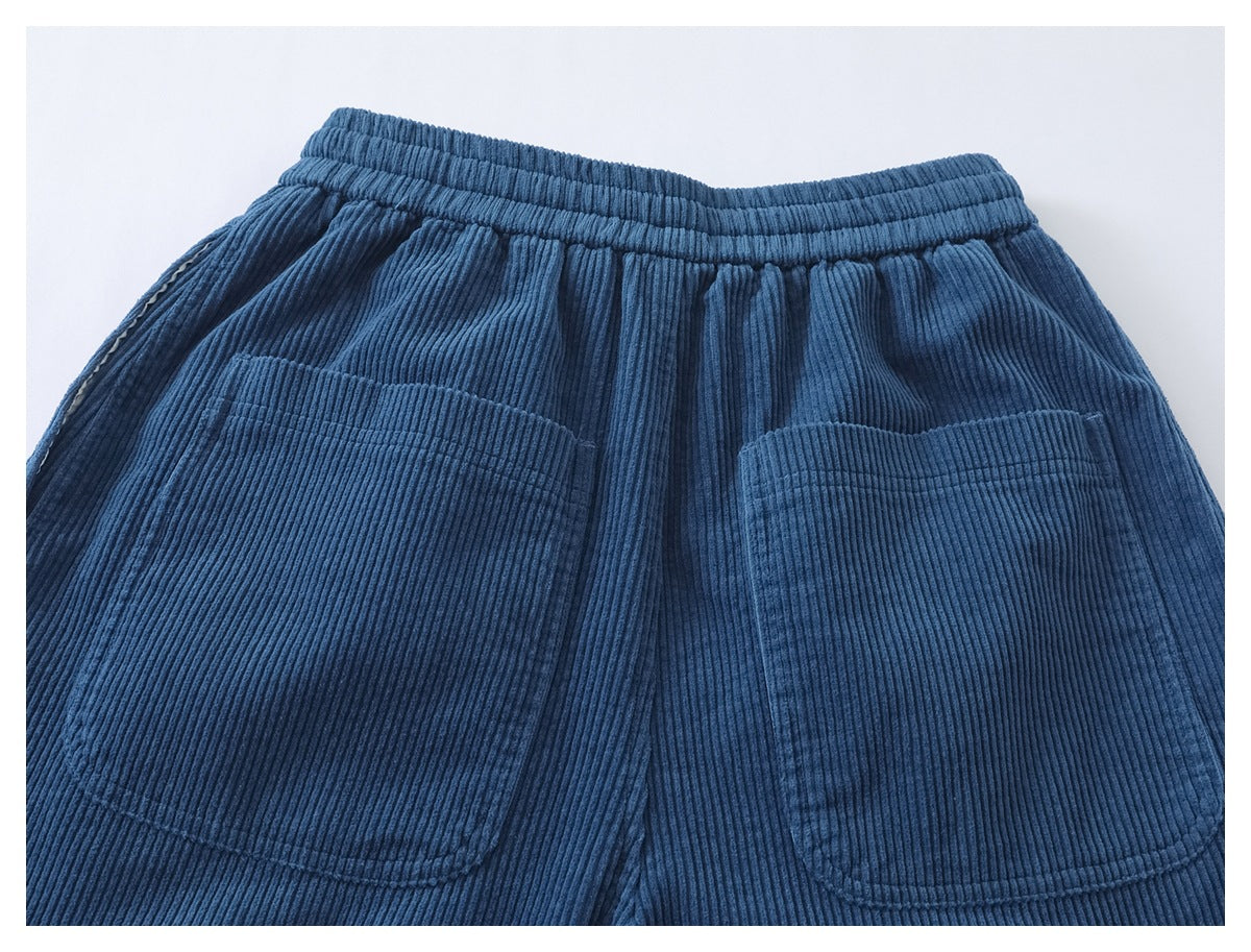 Rear view of blue ribbed corduroy pants with an elastic waistband and two large patch pockets.