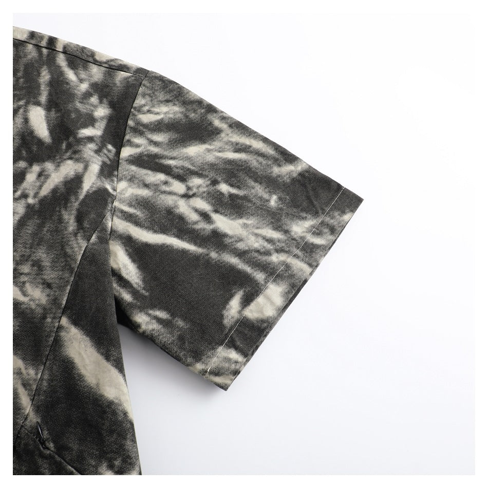Close-up of the short sleeve and shoulder seam on a black and cream abstract-patterned garment.