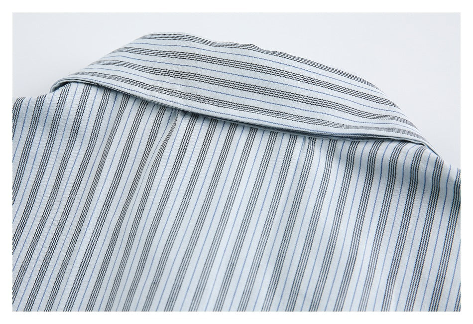 Close-up of a folded collar on a white shirt with fine blue and dark stripes.