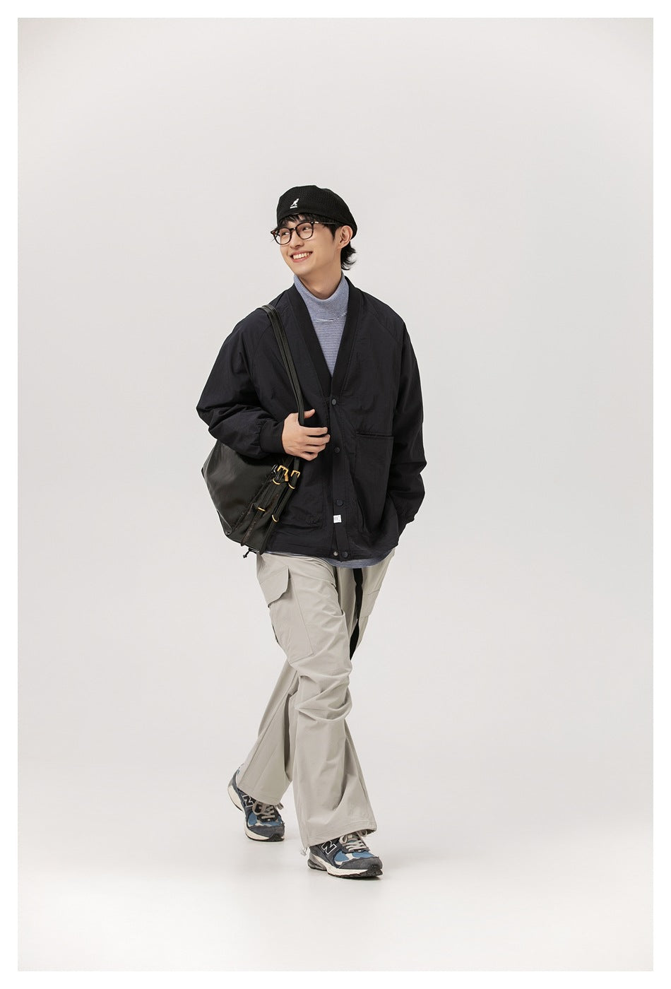 Full-length model wearing a black cardigan jacket, striped top, light gray cargo pants, and a shoulder bag.