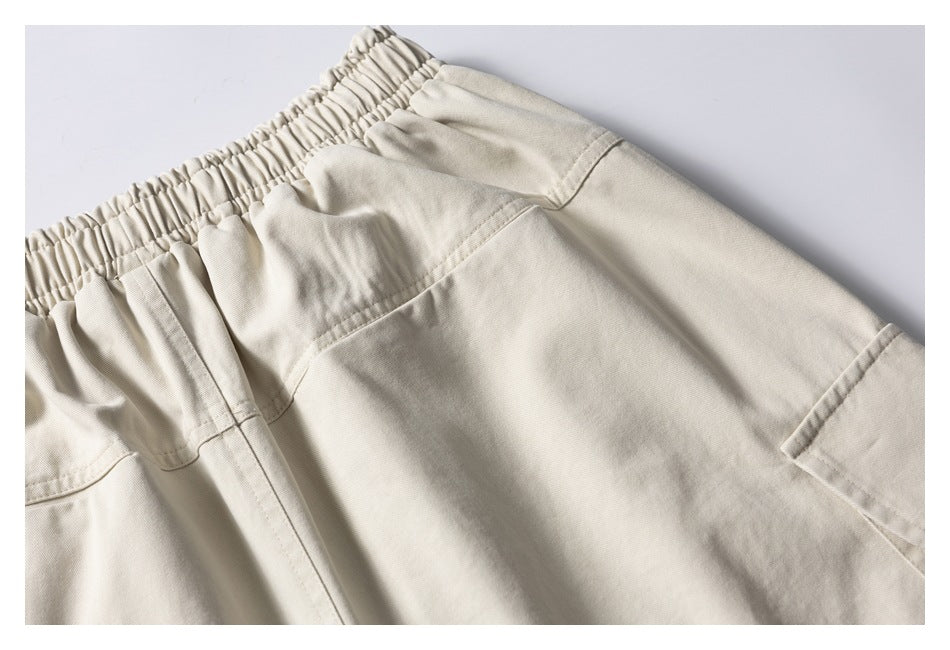 Angled close-up of light beige shorts showing the elastic waistband and cargo pocket.