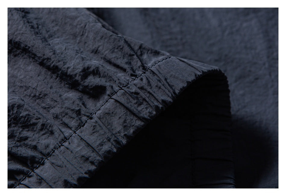 Close-up of a stitched garment edge with dark ribbed fabric visible beneath.
