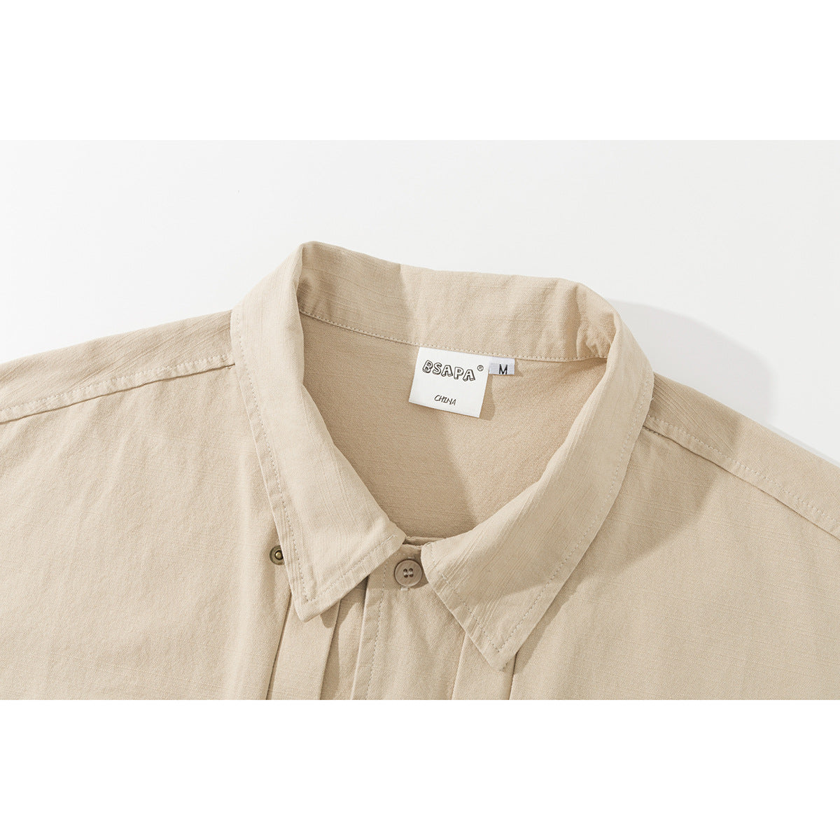 Close-up of a beige shirt collar, front placket, and sewn neck label.