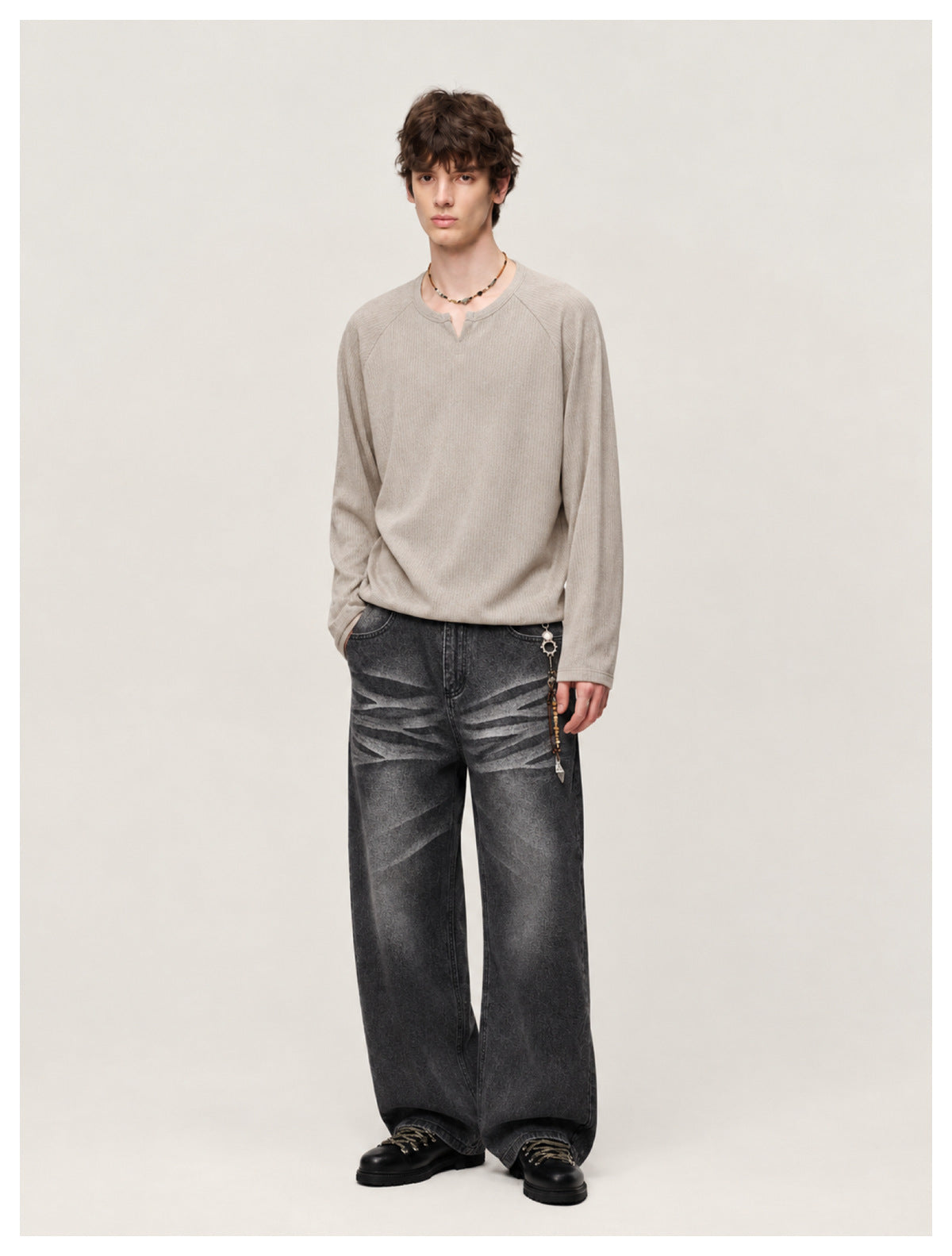 Front view of a model in washed black wide-leg jeans with whisker fading, taupe top and black lace-up boots