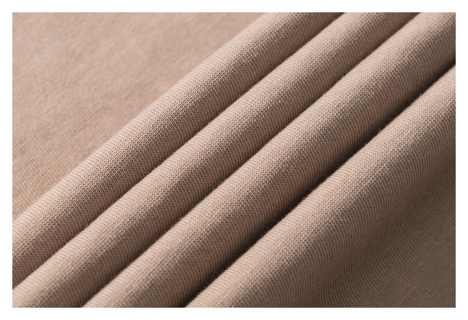Close-up of taupe knit fabric arranged in soft folds, showing its surface texture.