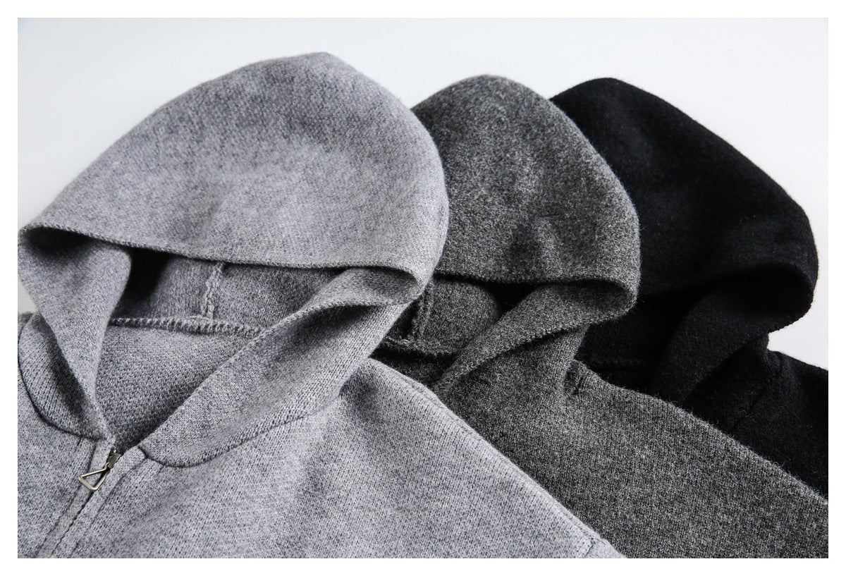 Close-up of light gray, charcoal gray, and black hooded sweaters, showing the hoods and a zipper on the light gray one.