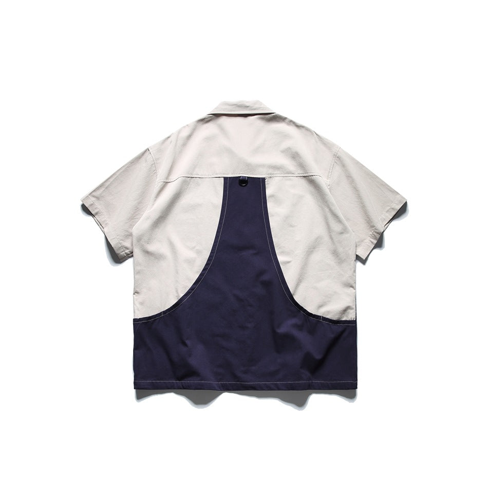 Back view of a light gray short-sleeve shirt with a large curved navy panel across the lower back.