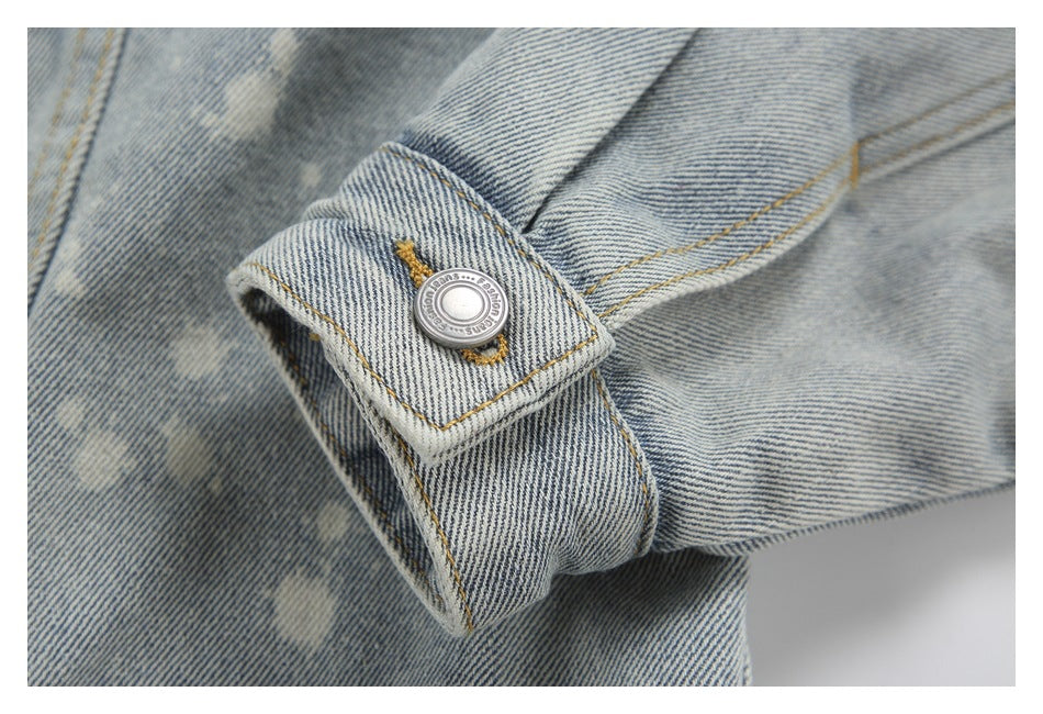 Close-up of the denim jacket's buttoned cuff with tan stitching and pale acid-wash marks.