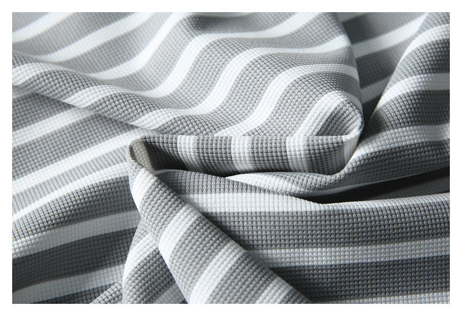 Close-up of gray and white striped fabric with a small waffle-like texture, draped in soft folds.