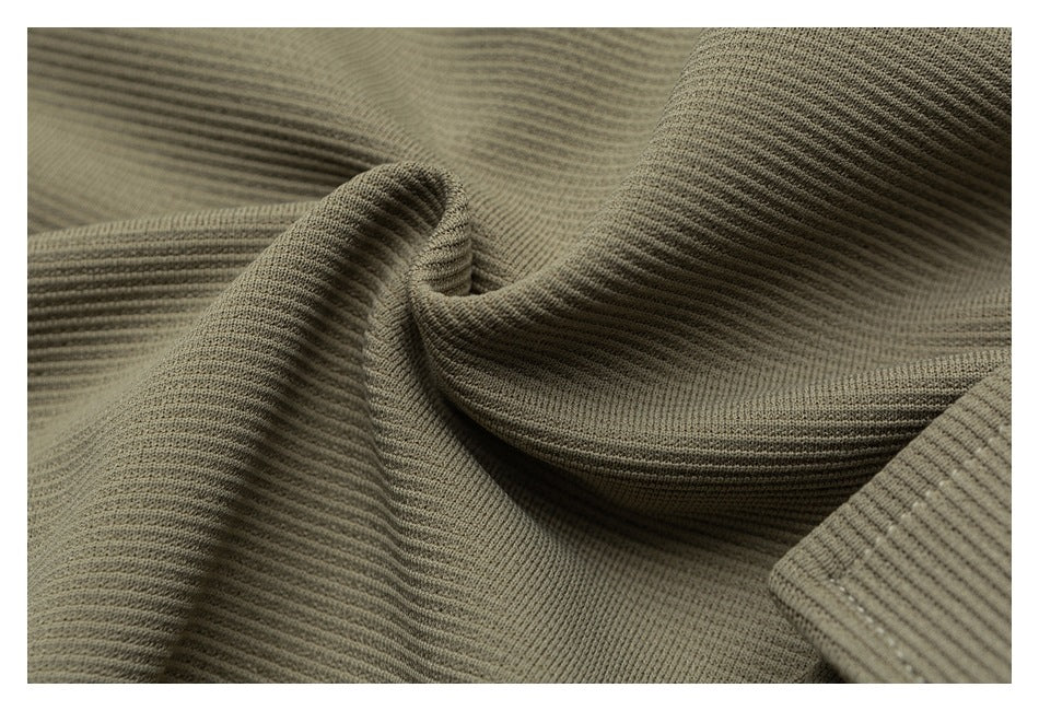 Macro view of olive-khaki ribbed fabric draped to show its texture and folds.