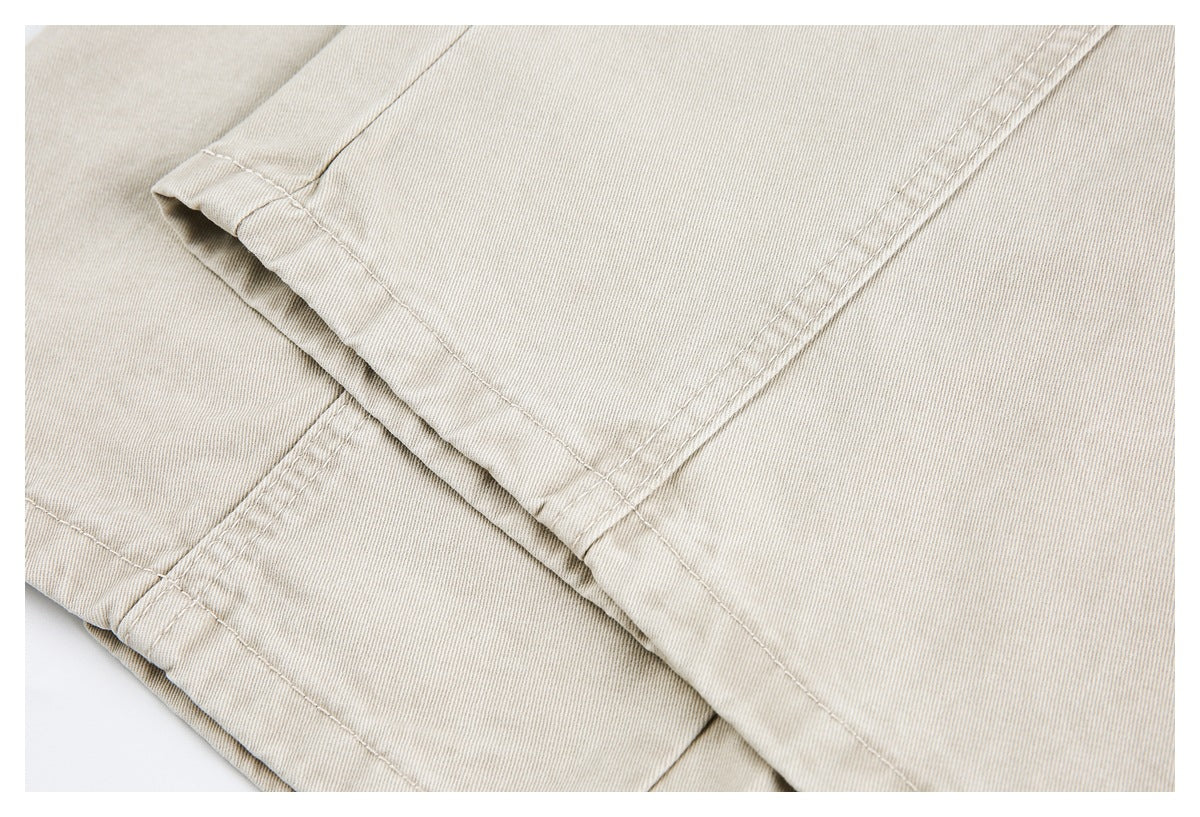 Close-up of overlapping stitched panels and a folded edge on light beige pants.